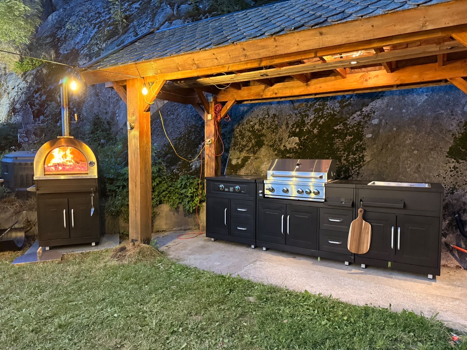 Outdoor kitchen with wood-fired pizza oven under the pergola